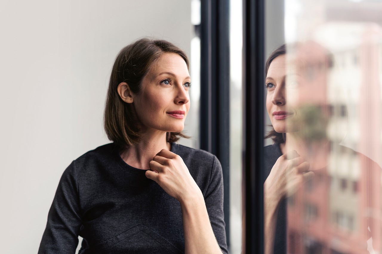 Woman looking horizon Thoughtful businesswoman looking through window in office.