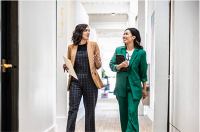 En savoir plus sur le modèle intégré de BNP Paribas groupe  Deux femmes habillées en costumes, discutant en marchant dans des bureaux