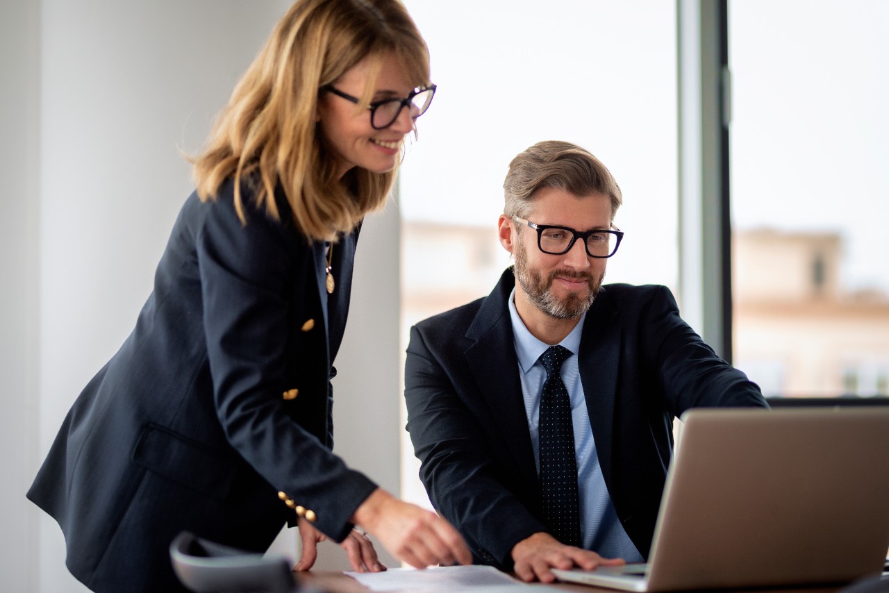 Happy man showing information on his computer to a happy woman