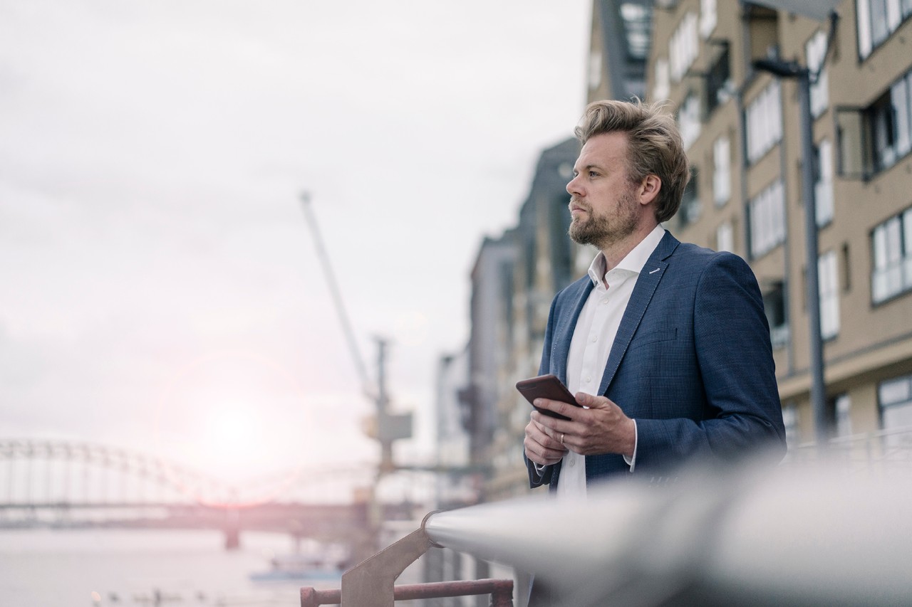 A man holding a phone on the banks of a canal